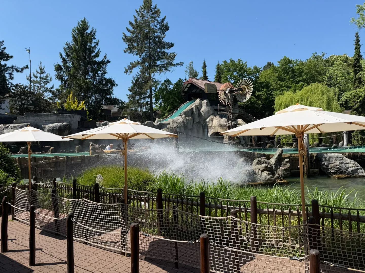 Wasserfontänen, Sonnenschirme und Bäume an einem Teich im Europa-Park