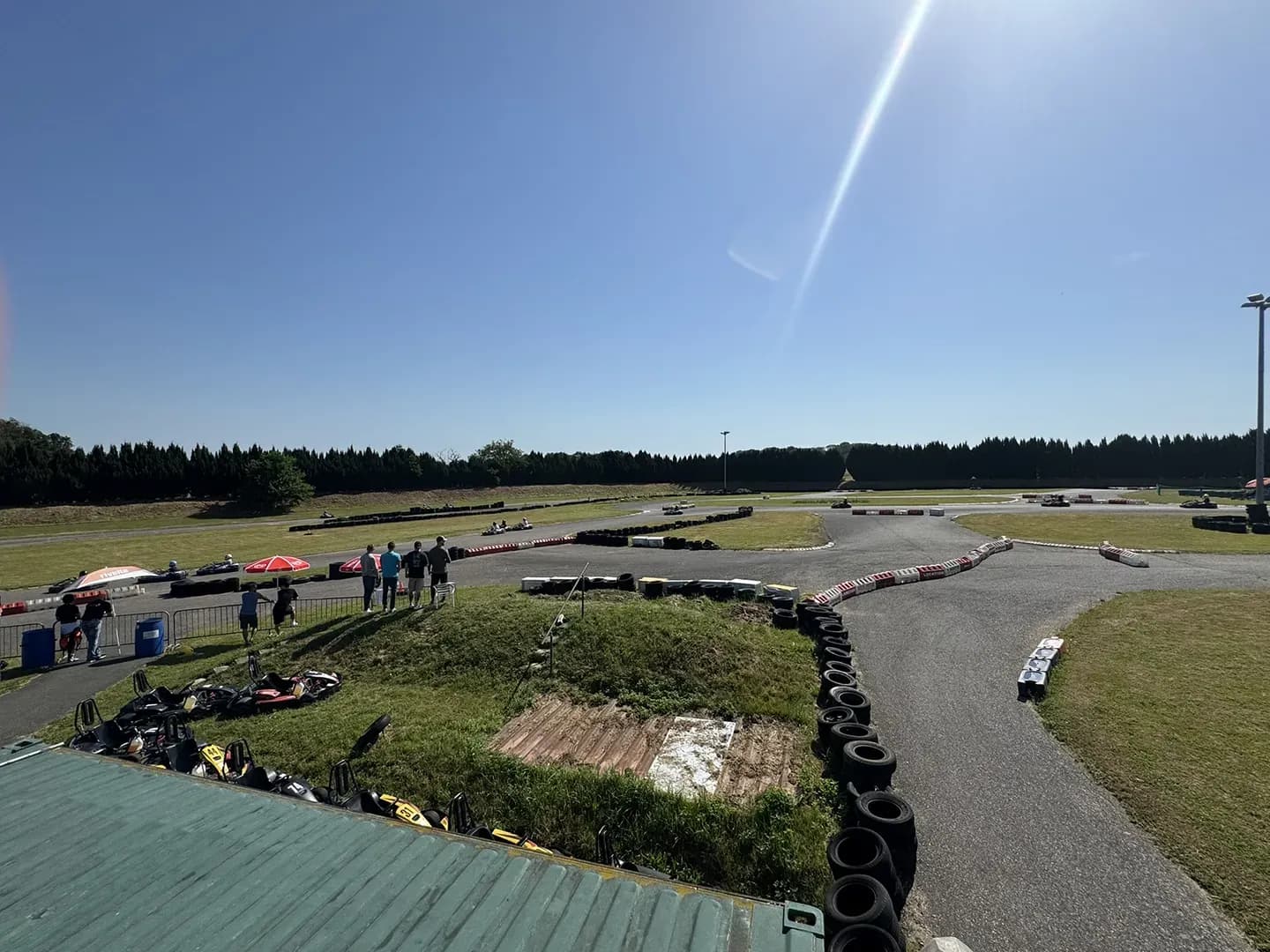 Blick über die Kartbahn im Sundgau mit Reifenstapeln, Karts und Zuschauern am Streckenrand