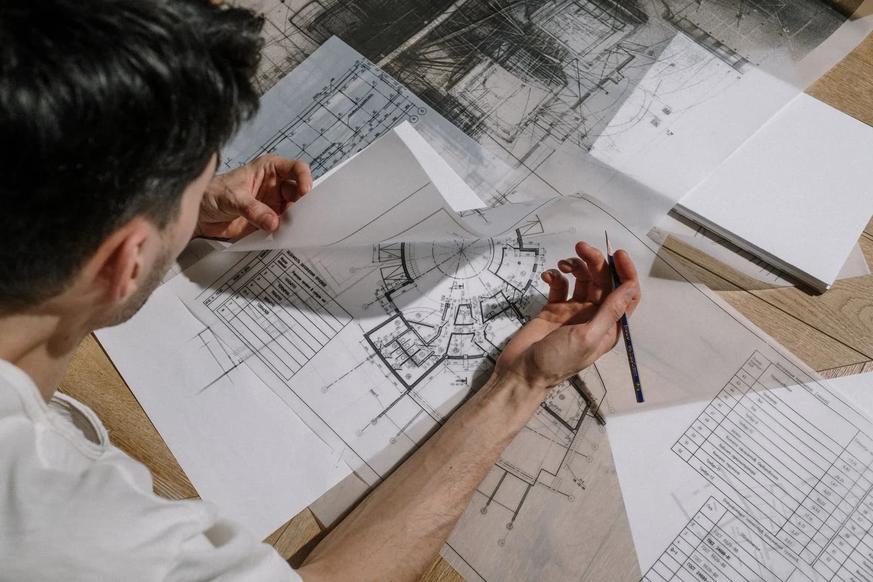 Ein Planer skizziert über ausgebreiteten Bauplänen